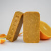 Savon artisanal orange Agrumes et Urucum avec zests d'orange et demi orange tranchée