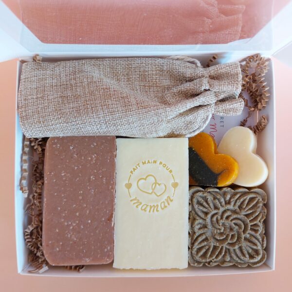 Coffret cadeau MöBiUS fête des mères, ouvert, avec savons, shampoing et accessoires sur fond saumon.