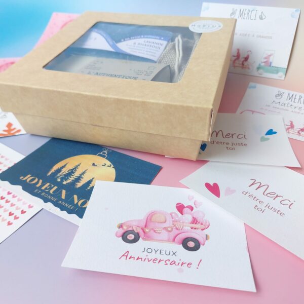 Coffret cadeau MöBiUS avec des cartes illustrées variées disposées tout autour : merci maître.sses, mamie chérie, joyeuses fêtes, et plus encore.