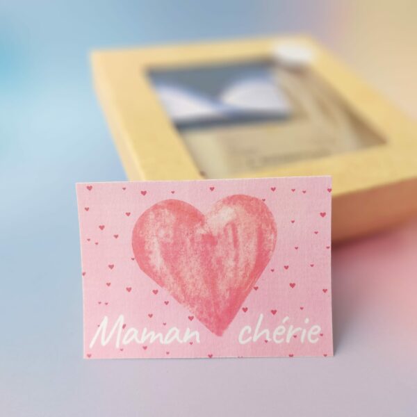 Carte "Maman chérie" avec un grand cœur rouge peint sur un fond rose parsemé de petits cœurs rouges.