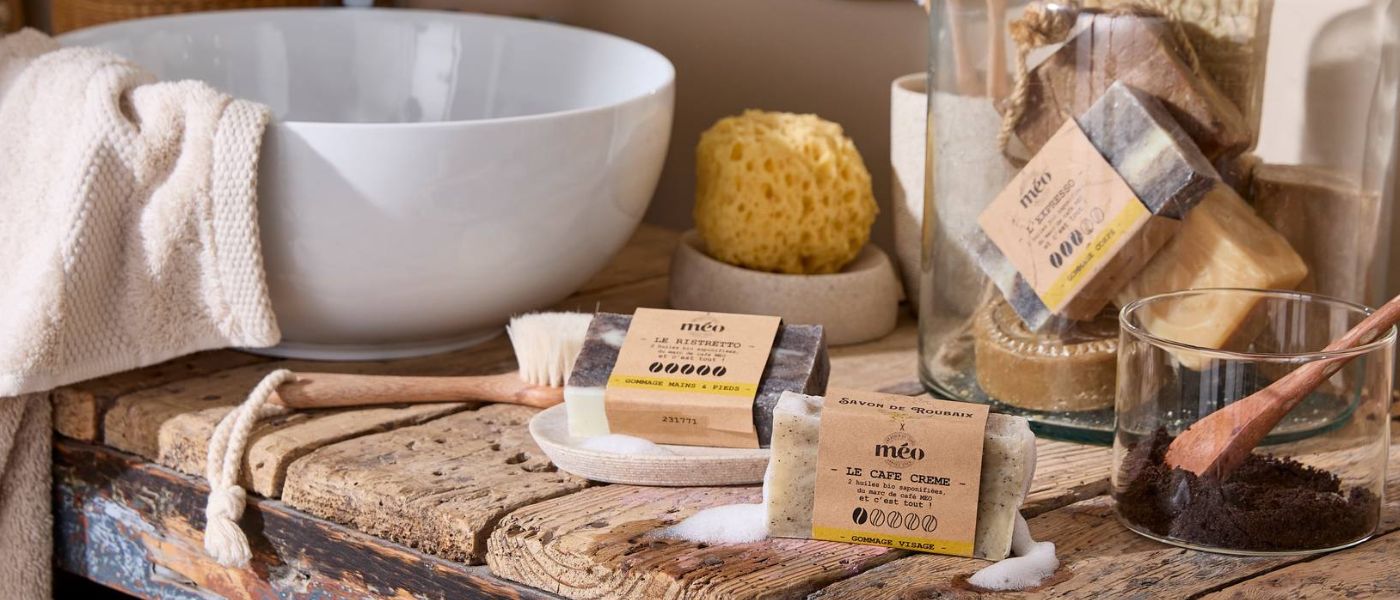 Bannière illustrant les savons de Roubaix au marc de café Méo pour gommage visage, corps, pieds et mains. Présentation dans une salle de bain authentique avec bois vieilli, vasque bol et accessoires naturels.