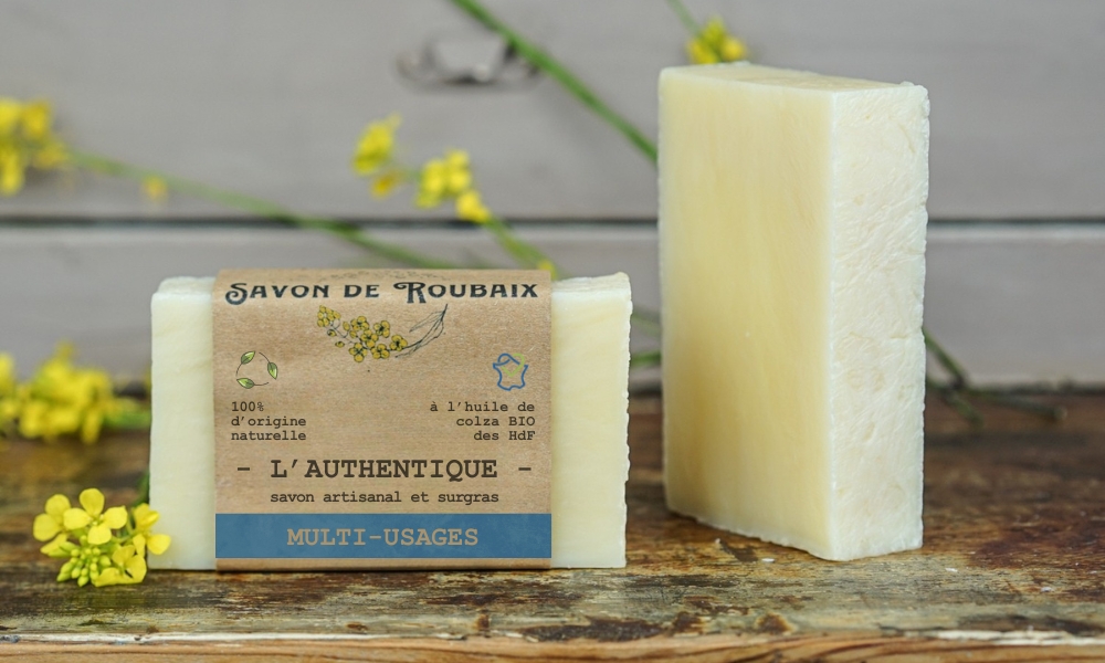 Savon de Roubaix artisanal posé avec une fleur de colza, savon emballé et savon nu fabriqués dans les Hauts-de-France