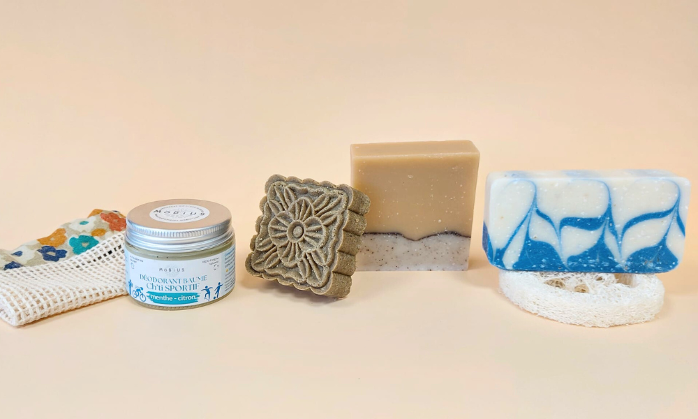 Soins cosmétiques solides Möbius sur fond orangé pastel : savon naturel, shampoing solide, déodorant Ch’ti Sportif et filet sauve-savon zéro déchet