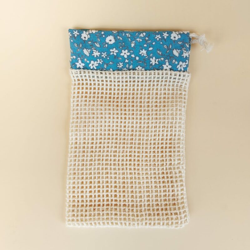 Vue du filet à savon artisanal MöBiUS : en tissu filet de coton et bande décorative upcyclée, proposé ici dans sa déclinaison turquoise à fleurs blanches