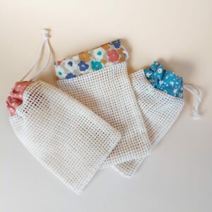Trois filets à savon MöBiUS en tissu filet de coton, chacun avec une bande de tissu upcyclé différente : turquoise à fleurs blanches, corail à pois blancs et beige à fleurs bleu-orange-corail.
