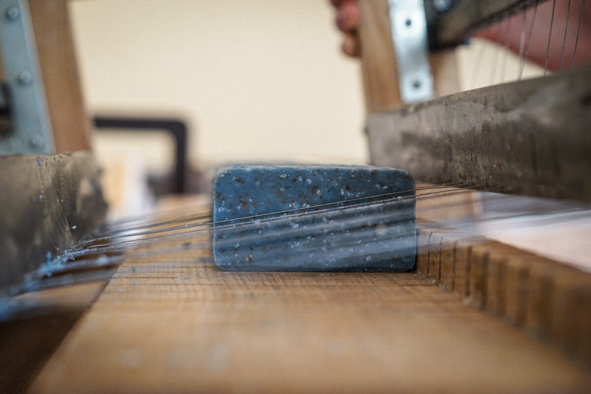 Pain de savon saponifié à froid lavande & rhassoul en cours de découpe avec le découpeur guitare-multifils dans l’atelier.