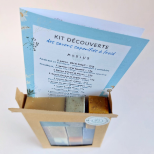 Coffret kraft du Kit Découverte MöBiUS vu de dessus, avec la fiche d’informations partiellement visible à l’arrière en arrière-plan flou.