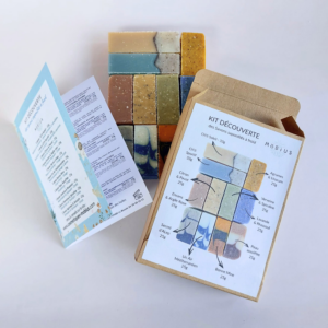Kit Découverte MöBiUS comprenant une fiche d’informations, 11 mini-savons saponifiés à froid et un coffret kraft ouvert, présentés sur fond clair.
