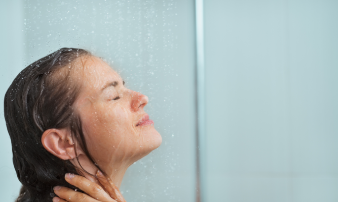 Femme sous la douche à l’eau tiède en hiver, illustrant les gestes doux pour éviter la peau sèche