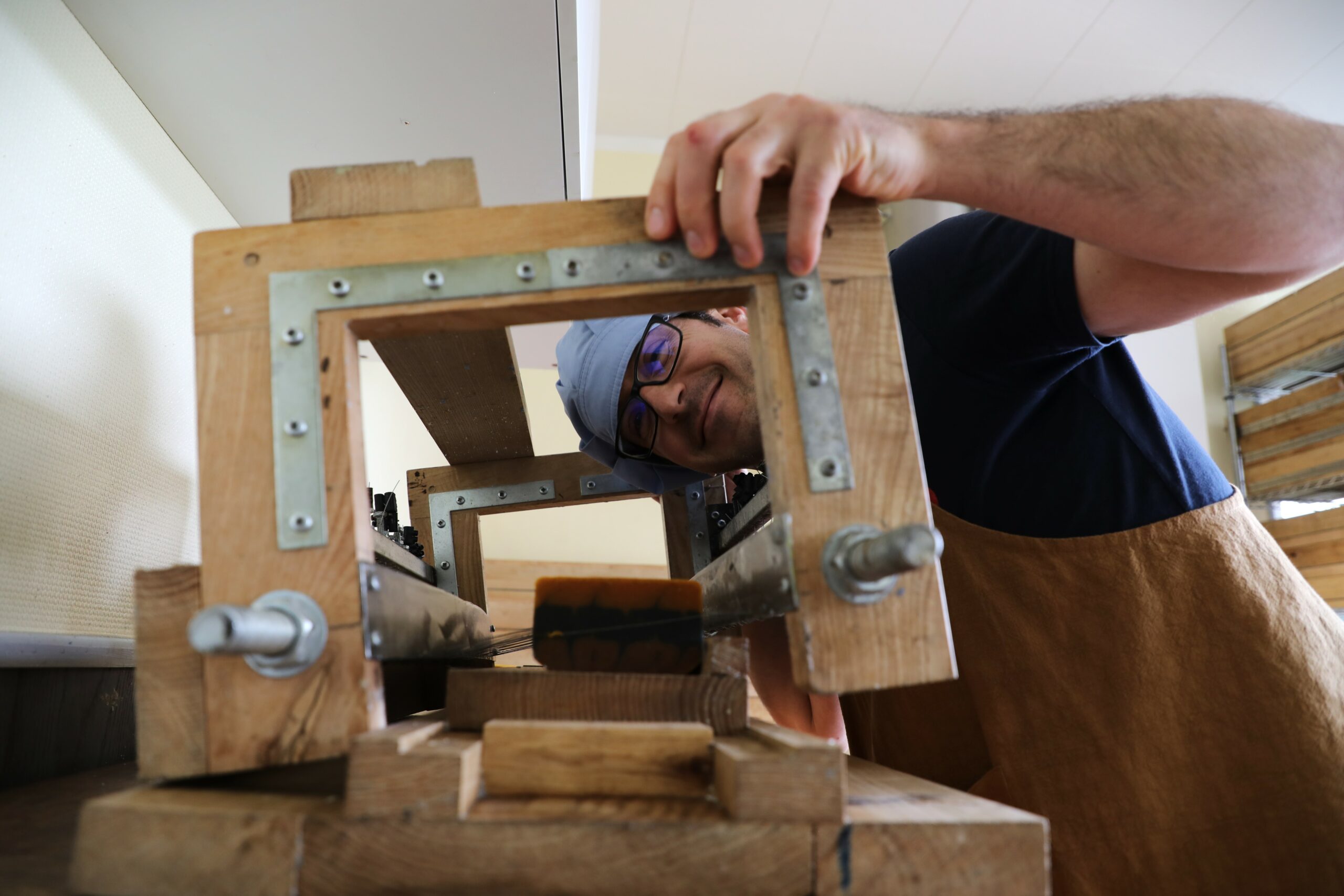 Hubert découpe un pain de savon à l’aide d’un coupe-savon manuel