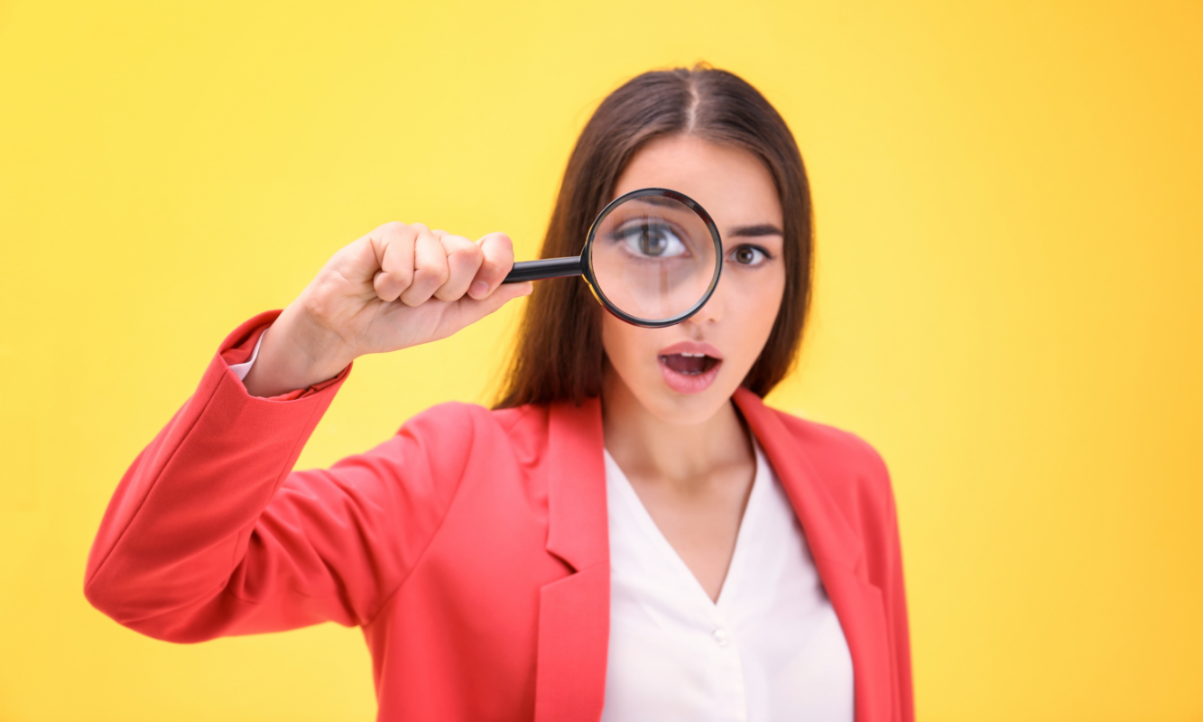 Femme observant à la loupe une liste d’ingrédients pour apprendre à comprendre la composition d’un savon