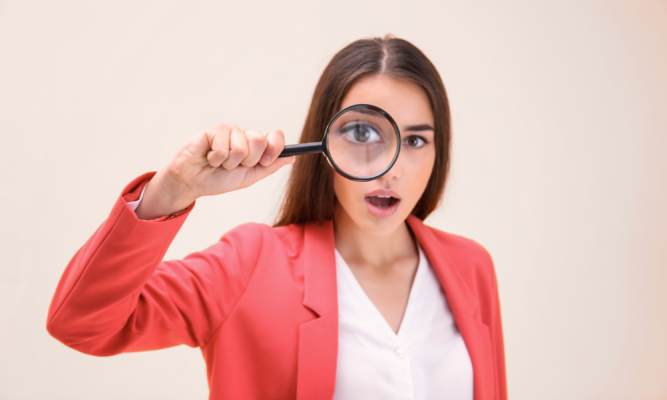 Femme observant à la loupe une liste d’ingrédients pour apprendre à comprendre la composition d’un savon