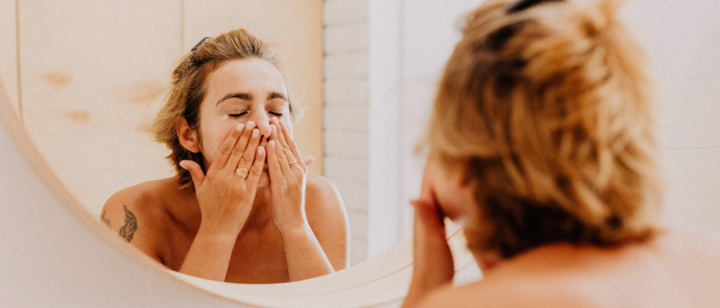 Femme se démaquillant le visage devant un miroir avec un lait démaquillant solide naturel